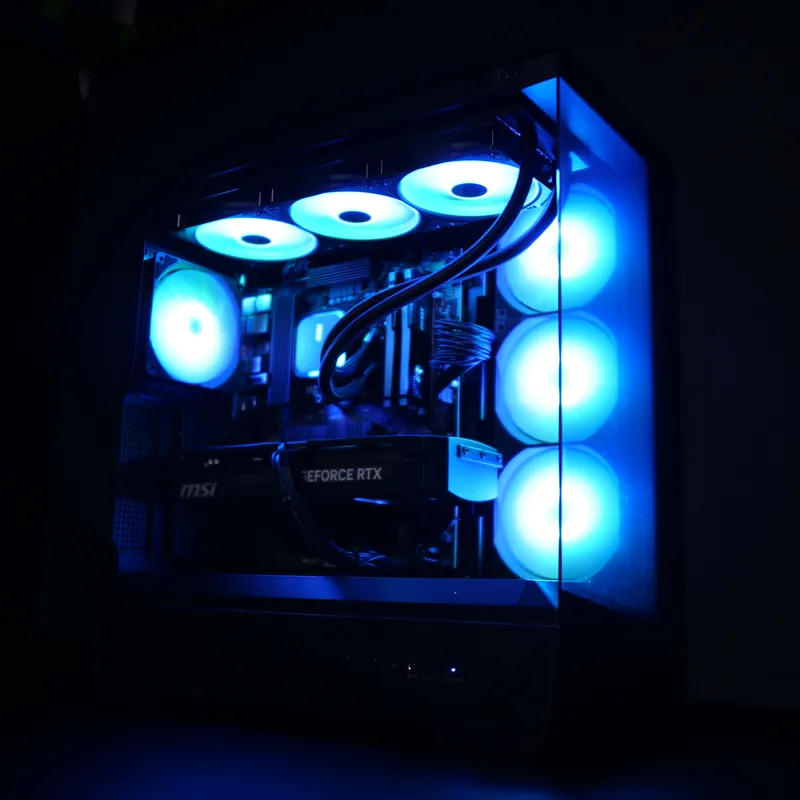MSI MAG PANO 130R PZ in Schwarz, ganzes Gehäuse schräg von vorn, cyan beleuchtet, Lüftersäule rechts hinter Glas