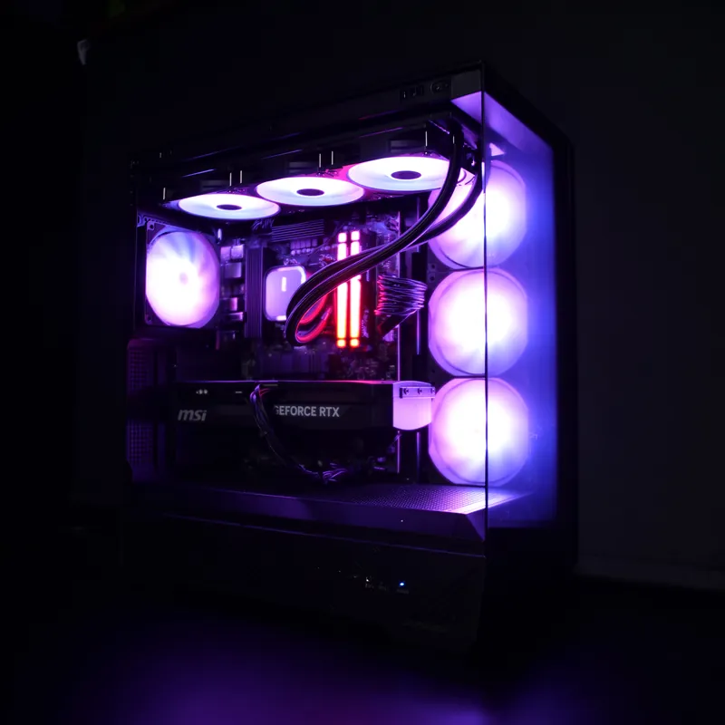 MSI MAG PANO 130R PZ in Schwarz, ganzes Gehäuse schräg von vorn, violett beleuchtet, Glasfront und Glasseite